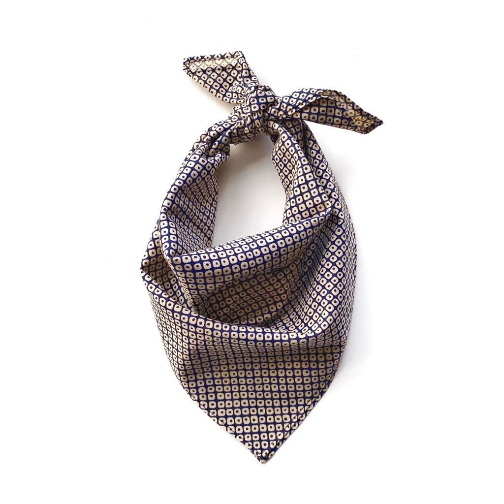 A Japanese geometric print cotton square neck scarf in navy blue and beige, tied in a bow at the top, shown on a plain white background.