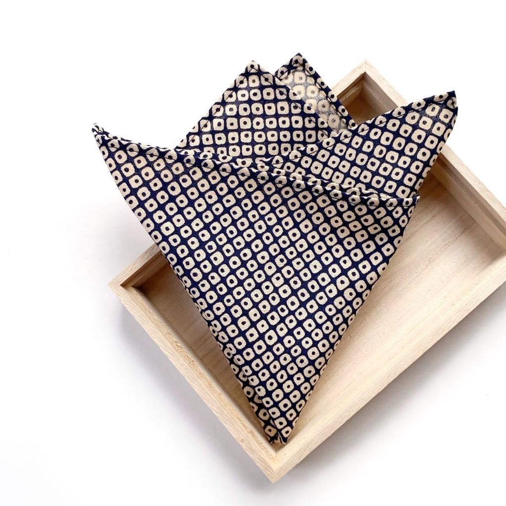 folded navy Japanese geometric print cotton pocket square on a wooden tray with a white background