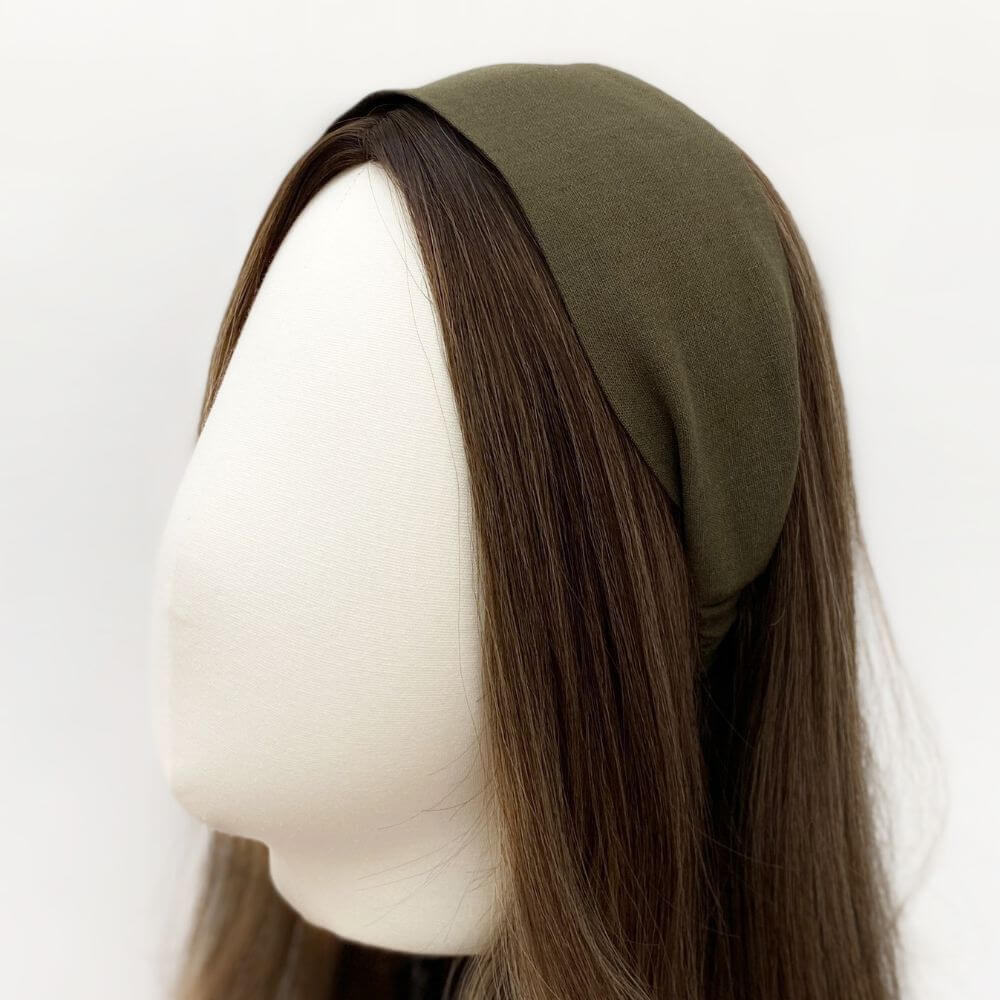 Mannequin head with brown hair wearing an olive green linen headband on a white background