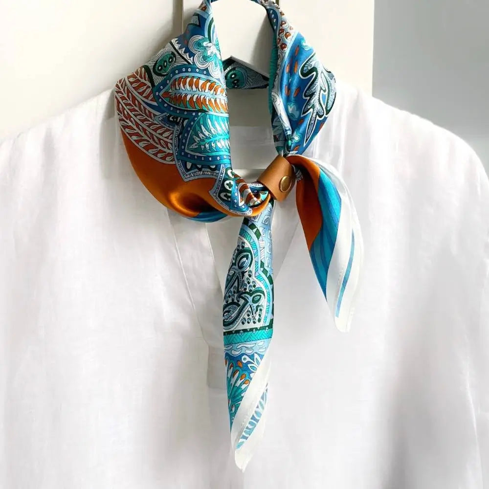 Leather scarf ring clip holding an orange and blue mulberry silk neck scarf on a hanger with a white shirt.