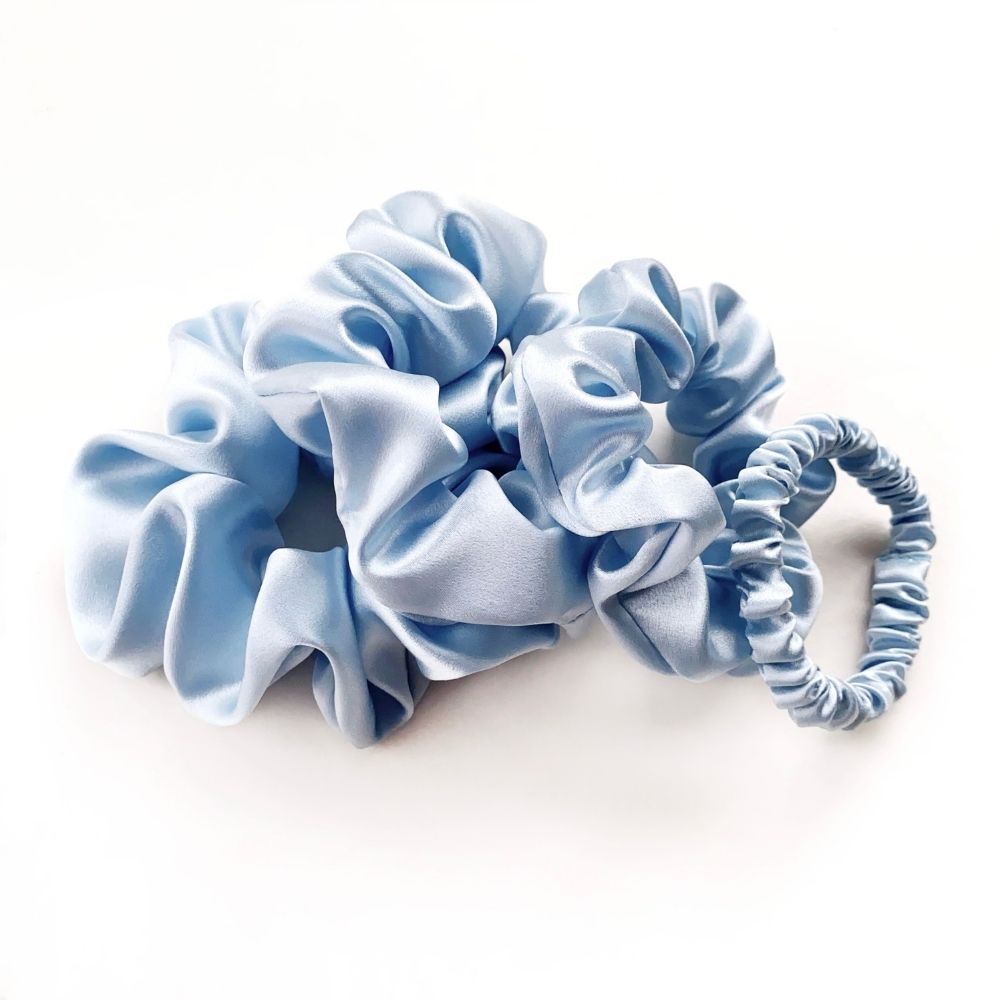 Set of light blue pure mulberry silk scrunchies and hair ties on a white background
