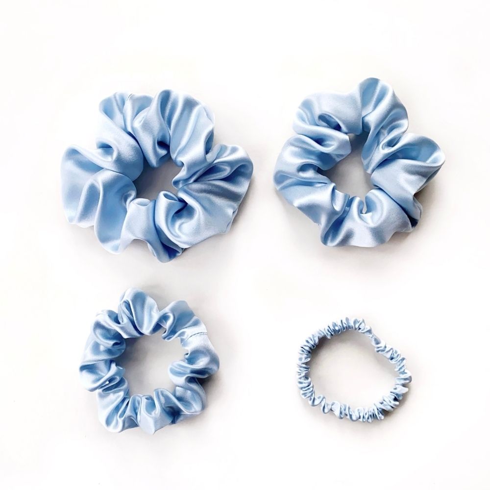 Set of light blue pure mulberry silk satin scrunchies and hair ties on a white background
