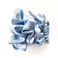 Set of light blue pure mulberry silk scrunchies and hair ties on a white background