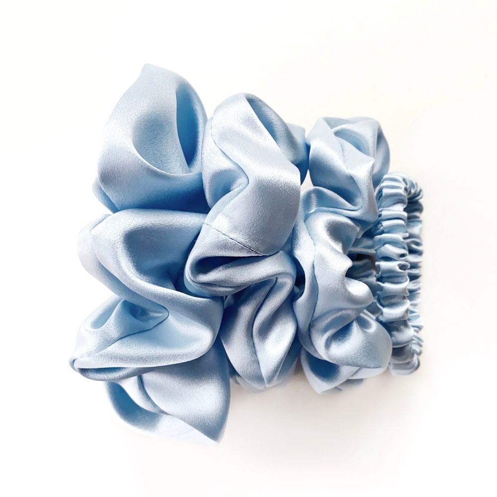 Set of light blue pure mulberry silk scrunchies and hair ties on a white background