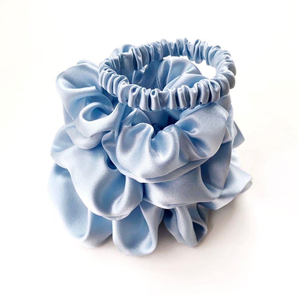 Set of light blue pure mulberry silk satin scrunchies and hair ties on a white background