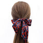  liberty silk skinny scarf wear as a hair bow with floral pattern tied around a ponytail on a white background