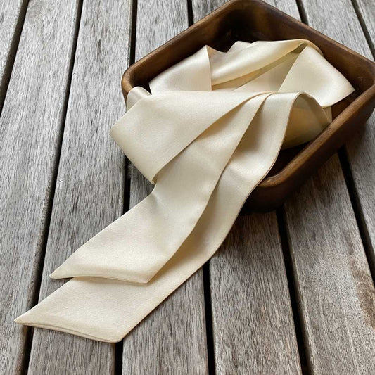 ivory cream coloured mulberry silk satin skinny scarf in the box, placed on the table 