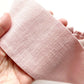 Close-up of a hand holding a pink linen headband.