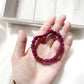 Hand holding a purple silk satin hair tie  with a light wooden box in the background