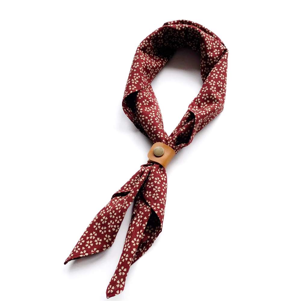 Red floral patterned scarf with a leather scarf clip on a white background