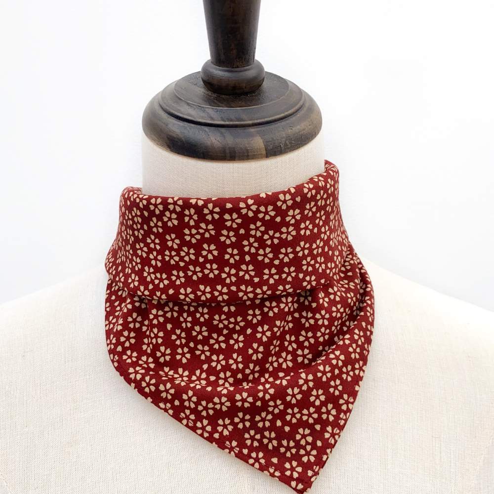 Red floral patterned bandana on a mannequin head with a white background