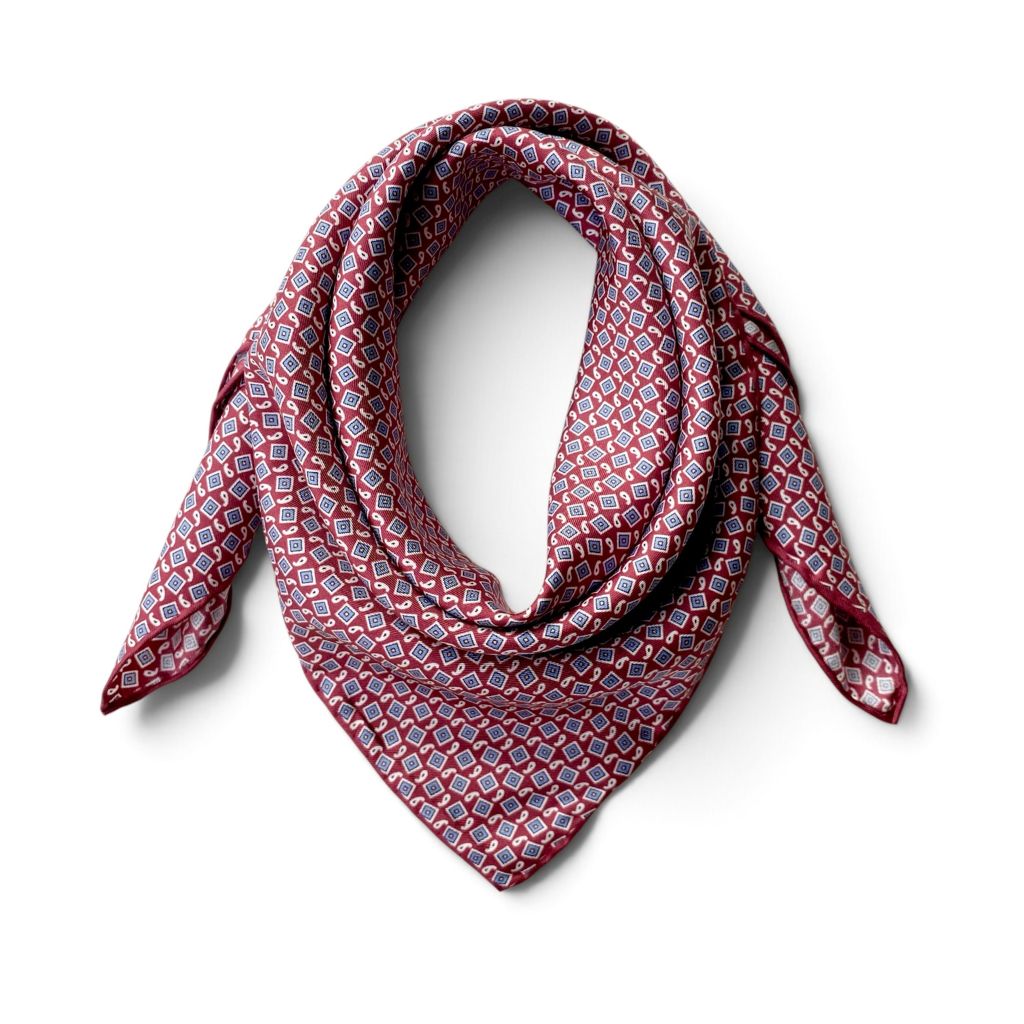 A deep red geometric and paisley print mulberry silk square scarf displayed on a white background