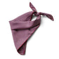 A deep red geometric and paisley print mulberry silk square scarf tied into a triangle, placed on a white background