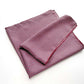 A deep red geometric and paisley print mulberry silk square scarf folded and laid flat on a white background