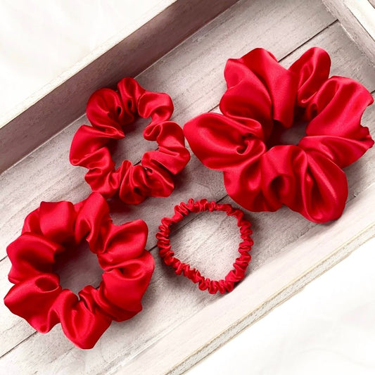 set of red mulberry silk satin scrunchies  and hair ties on the wooden surface