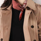 Woman wearing a khaki trench coat and black top with a red polka dot and paisley mulberry silk scarf tied around her neck.