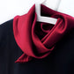 Berry red silk satin scarf tied neatly around a black top on a hanger