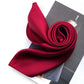 Berry red silk satin scarf rolled into a spiral and placed on an open magazine
