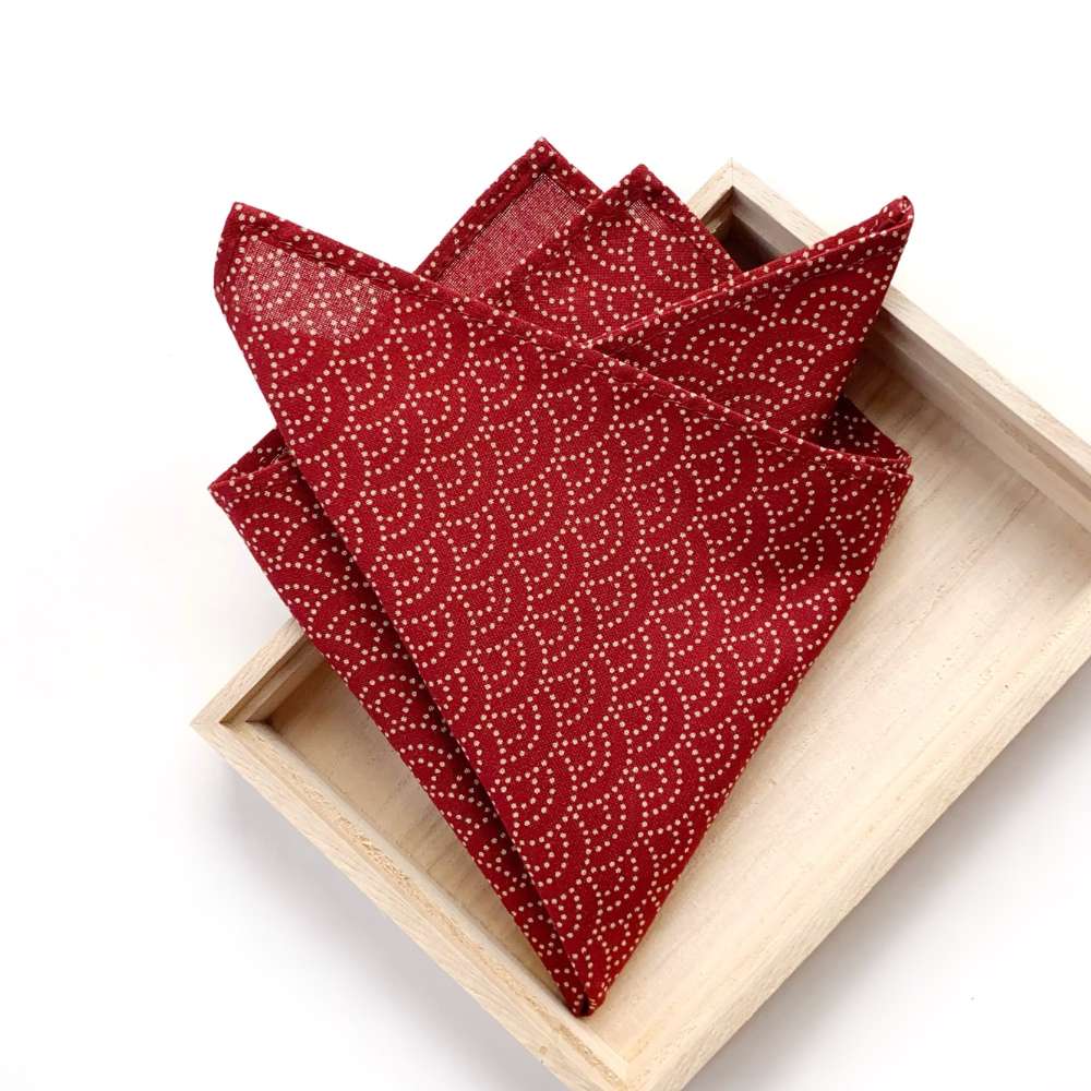 Red wave patterned Japanese cotton pocket square on a wooden tray with a white background