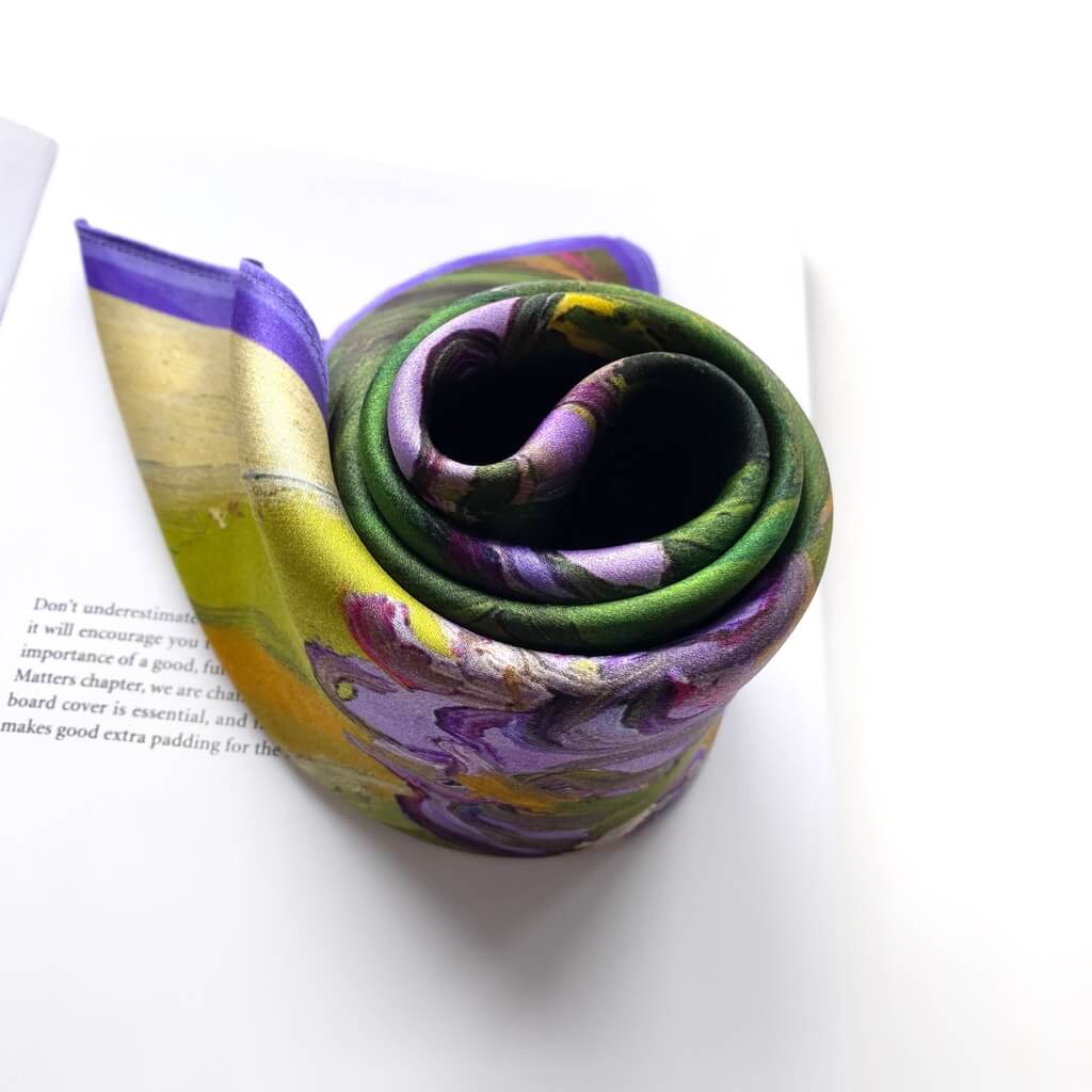 Rolled-up colorful mulberry silk square scarf on a white surface