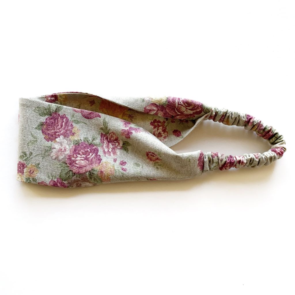 A sage green cotton linen fabric headband with a vintage floral rose pattern, featuring an elastic back, shown on a plain white background.