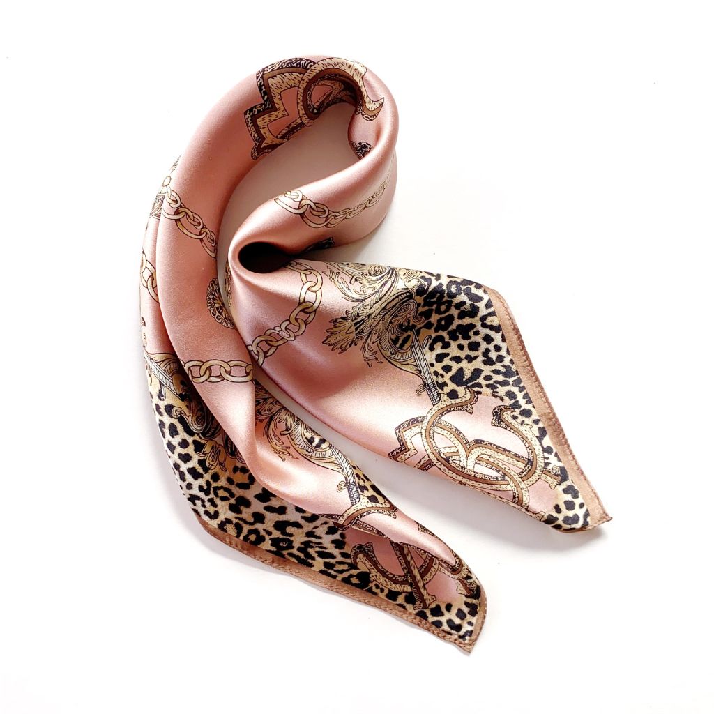 A square mulberry silk scarf featuring a mixed pattern of leopard print and gold chain motifs, styled in a loop on a white background.