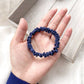 Navy blue silk hair tie held in a hand on a light wooden surface