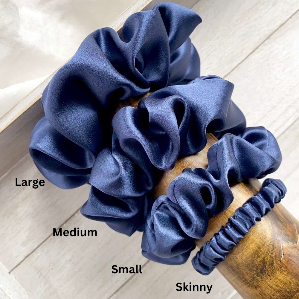 Set of blue silk hair scrunchies labeled with size on a wooden surface