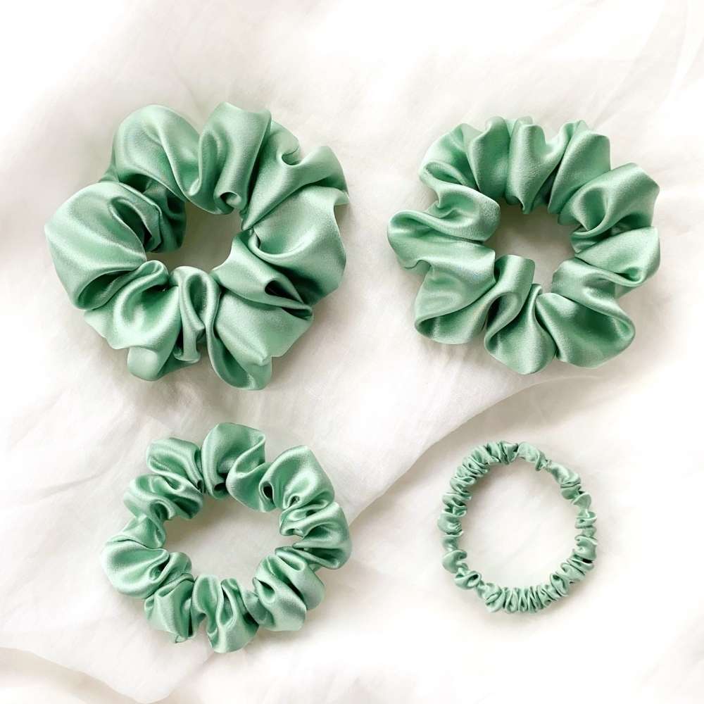 Four green silk scrunchies on a light background
