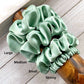 Set of four green silk scrunchies on a wooden handle with size labels.