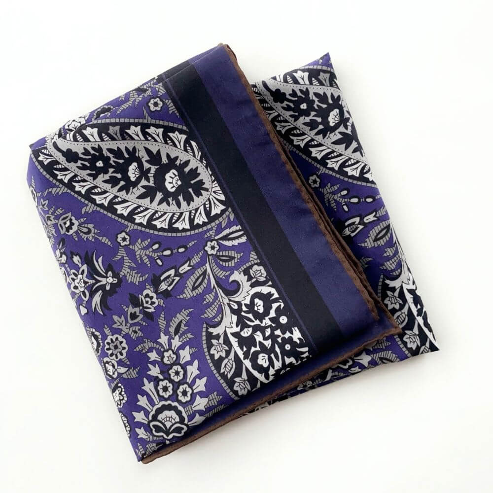 Folded purple paisley silk cotton blend scarf showing the border and intricate floral paisley pattern.