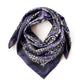 Purple paisley silk cotton blend square scarf folded and shaped into a neckerchief style on a white background.