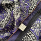 Detail shot of the purple paisley scarf with fabric label showing the 70% cotton and 30% silk blend composition.