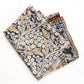 Folded yellow and teal paisley floral silk cotton blend square scarf displayed flat, showing layered prints.