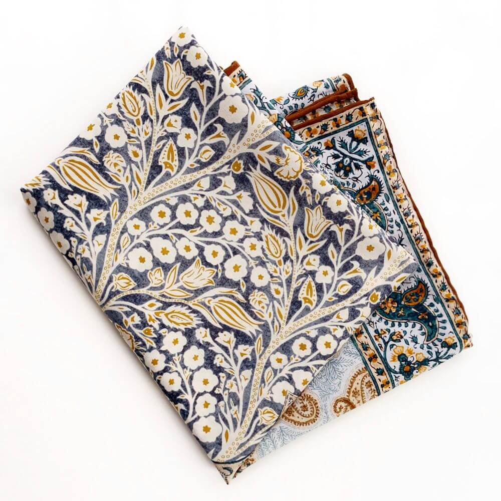 Folded yellow and teal paisley floral silk cotton blend square scarf displayed flat, showing layered prints.
