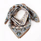 Yellow and teal botanical paisley silk cotton scarf styled in a loose loop on a white background.