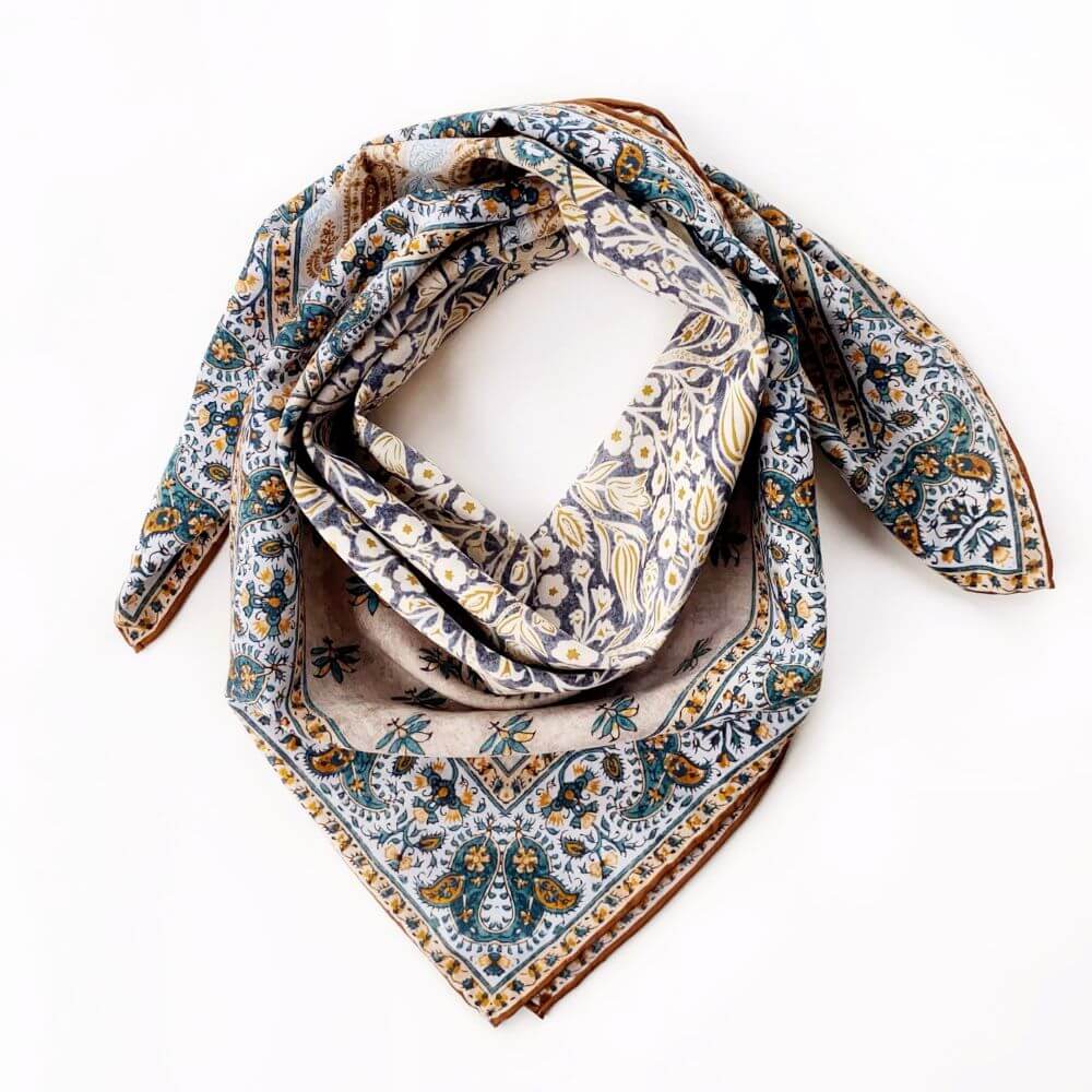 Yellow and teal botanical paisley silk cotton scarf styled in a loose loop on a white background.