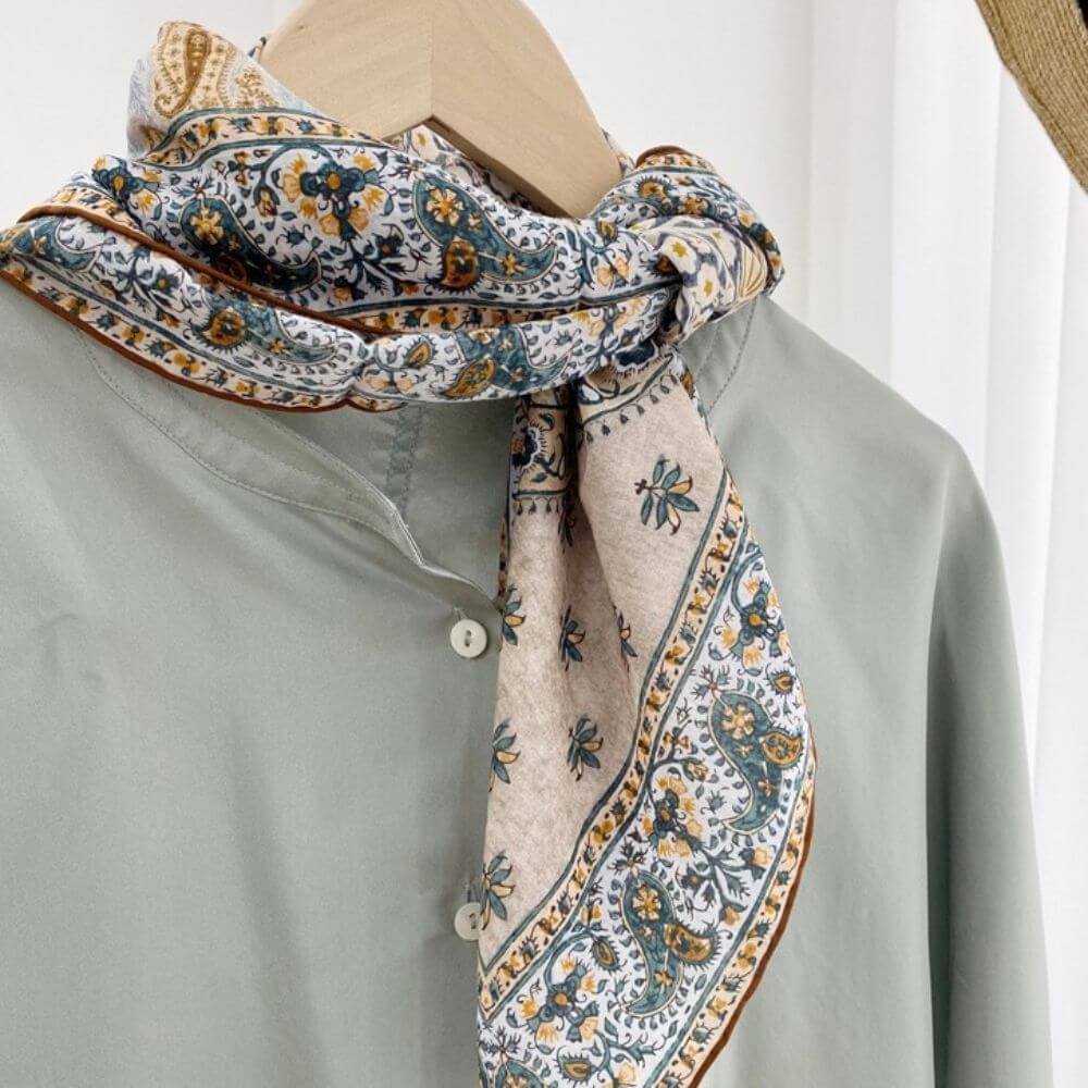 Silk cotton blend scarf tied in a simple knot around a shirt collar, showcasing the teal and mustard paisley border.