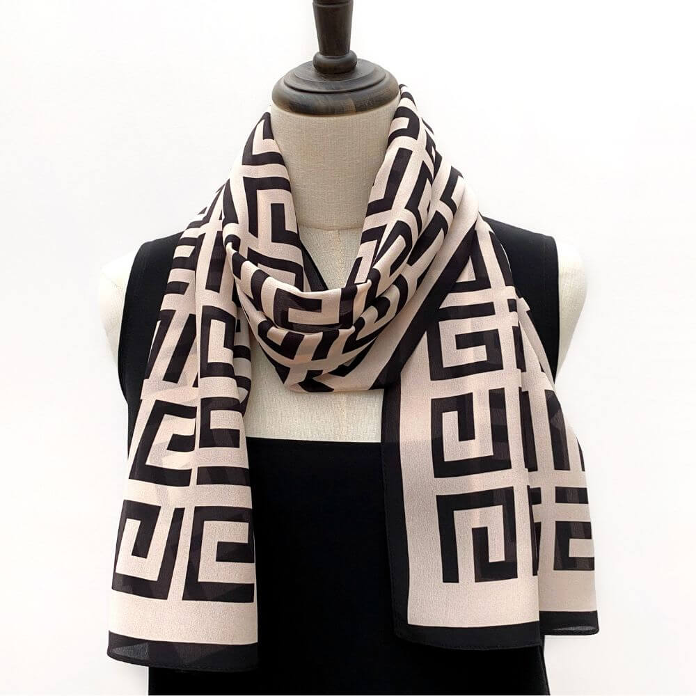 Long blush pink and black geometric Mulberry silk Crepe de Chine scarf styled on a mannequin, folded and draped loosely around the neck.