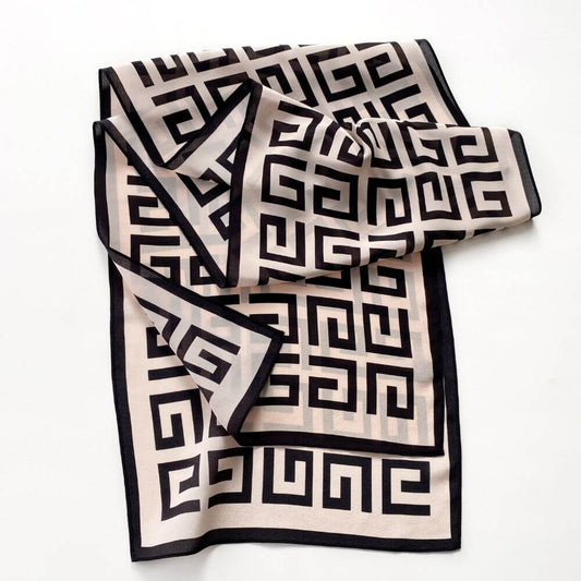 Blush pink and black geometric Mulberry silk scarf laid flat with soft folds, showing the maze-style pattern and border.