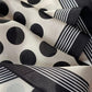 Close-up of the black polka dot pattern and striped border on the Mulberry silk Crepe de Chine scarf, showing the soft texture.
