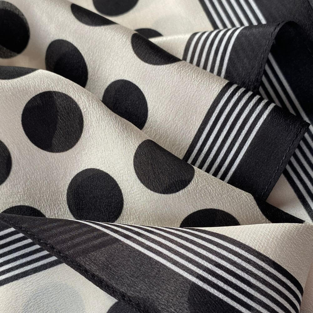 Close-up of the black polka dot pattern and striped border on the Mulberry silk Crepe de Chine scarf, showing the soft texture.