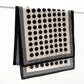 Black and white polka dot Mulberry silk Crepe de Chine scarf hanging over a horizontal rod, showing the border and repeating dot pattern.
