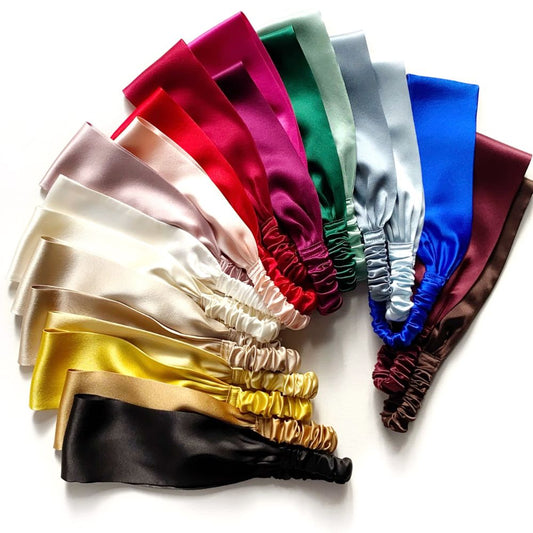 A set of mulberry silk satin elastic headbans in multiple colors, including white, black, gold, beige, pink, red, green, blue, silver, black, and brown, arranged in a fan shape on a white background.