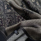 Detailed close-up of geometric maze and floral motifs on black silk satin.