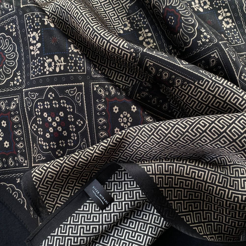 Detailed close-up of geometric maze and floral motifs on black silk satin.