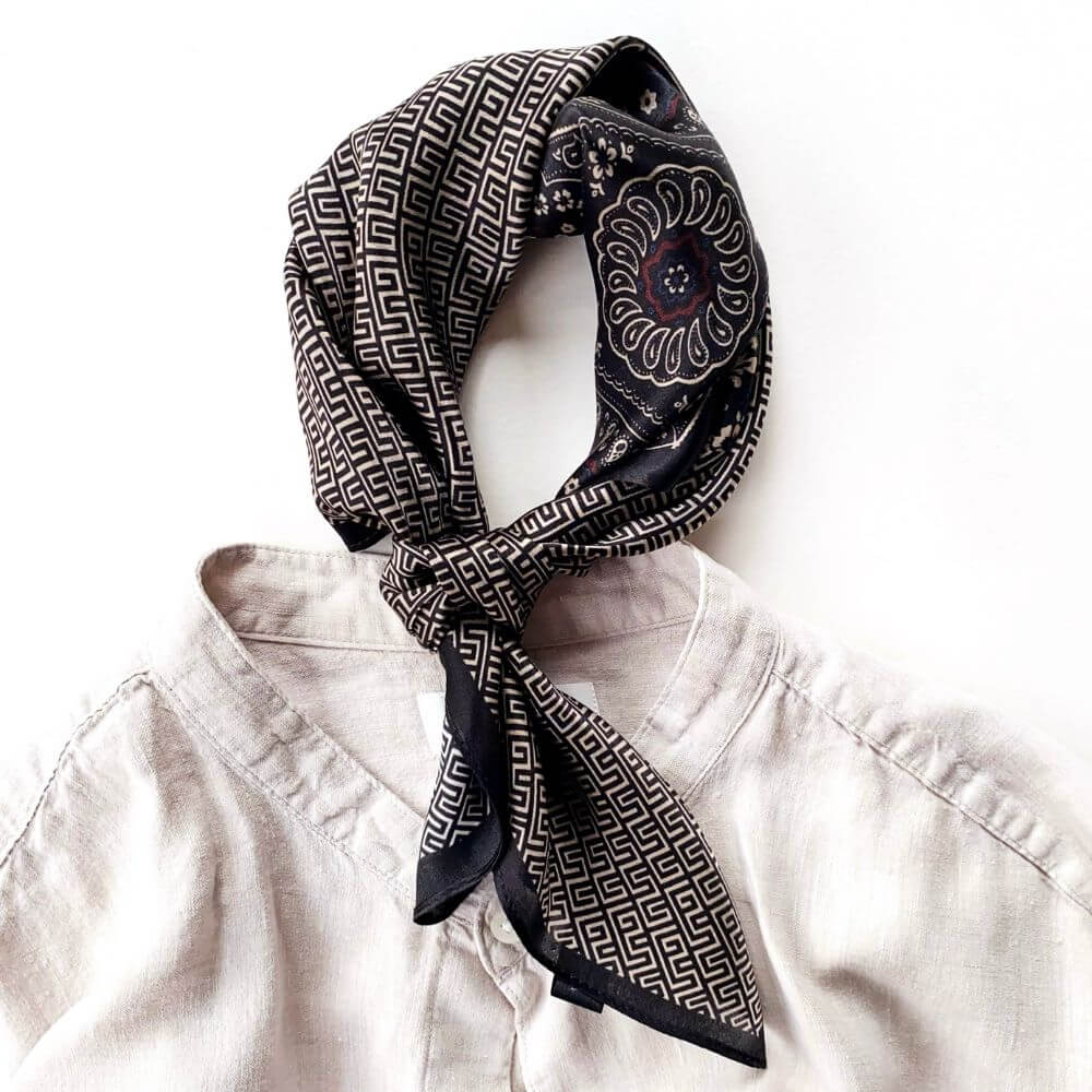 Black geometric floral silk scarf styled in a neckerchief on a neutral shirt