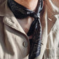 Man wearing black geometric floral silk scarf tied as a neckerchief