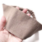 Brown linen fabric headband held in a hand against a white background
