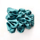 Set of teal blue pure mulberry silk satin scrunchies and hair ties on a white background